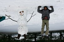 Jonathan stands on his head beside the snowman